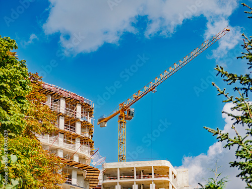Canvastavla Construction site with tower crane and unfinished apartment building against blu