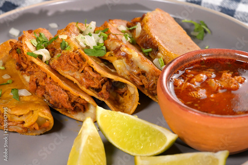 Appetizing plate of fried shredded pork tacos with chopped onions and fresh herbs, ready to serve