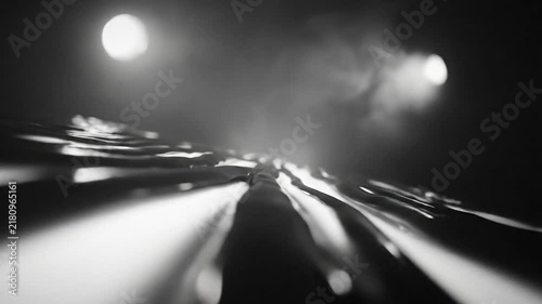 Abstract grayscale shot of a flowing liquid surface with bright light sources and a dark background