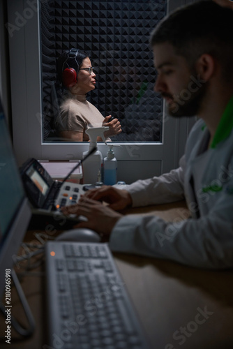 Contemplative woman with headphones and man in lab coat at office