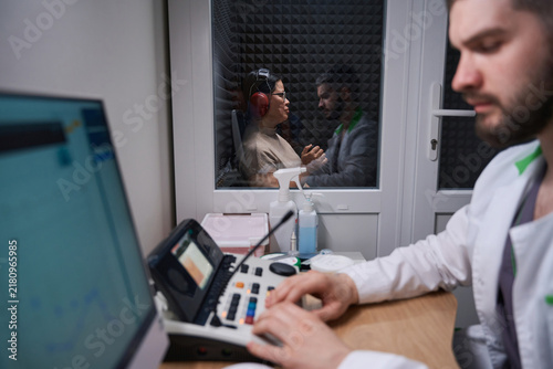 Adult male and female in soundproof booth at medical clinic
