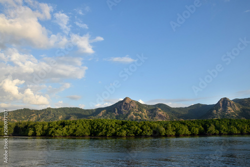 Sailing to Komodo Island in clear weather, passing rugged hills amidst the crystal-clear waters of Rinca Island, Labuan Bajo, Indonesia.