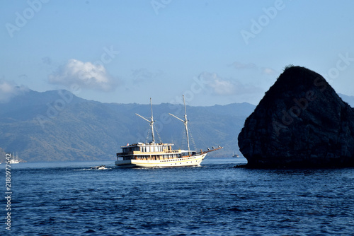 A Phinisi boat carrying tourists amidst the beautiful, rugged hills of the Komodo National Park area, Labuan Bajo, Indonesia