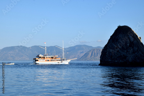 A Phinisi boat carrying tourists amidst the beautiful, rugged hills of the Komodo National Park area, Labuan Bajo, Indonesia