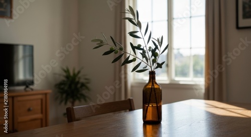 Interior shot of a dining room with olive branch in a brown glass bottle