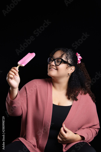 Happy woman looking at pink popsicle with black background