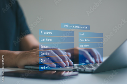 A man entering personal information on an online registration form via a laptop and smartphone. Digital data privacy, cybersecurity, identity verification and secure account sign up concept.