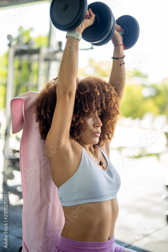 Fotografie Woman exercising overhead press with dumbbells for strength