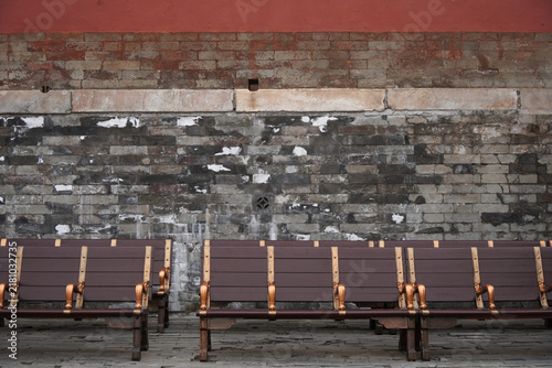 Fotografie Row of Benches Against Old Brick Wall