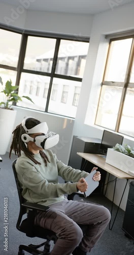 Vertical video: Non-binary person testing VR sim with headset activating, steering wheel in office