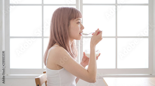 Obraz w ramie 窓辺でヨーグルトの朝食を楽しむ若い日本人女性