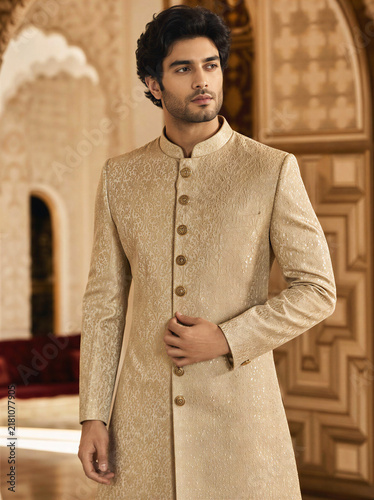 Elegant Male Model in Gold Embroidered Sherwani Suit Standing in Palace Interior