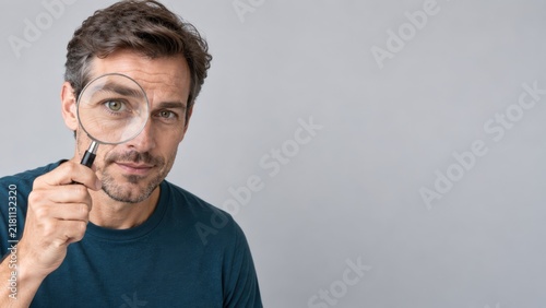 Curious Mature Man Looking Through Magnifying Glass with Copy Space