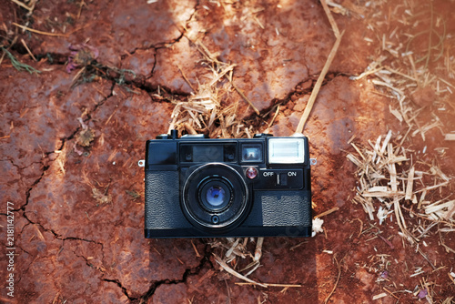фотографія Top view of vintage black film camera on parched mud and cracked red earth