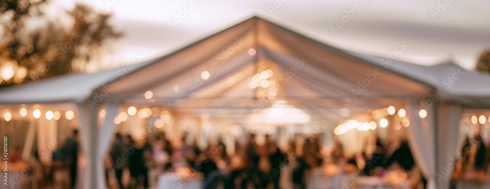Naklejka premium Outdoor event in a large white tent with guests celebrating, blurred background 