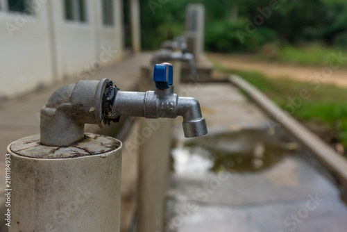 Foto Metal water tap with a blue handle attached to a concrete post
