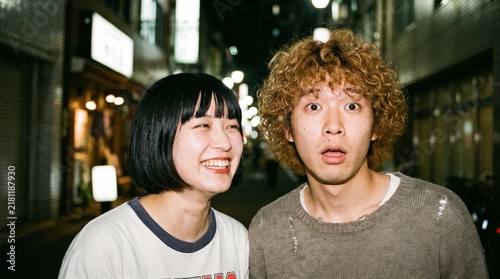 夜の街で笑顔と驚いた表情を見せる日本人の若いカップル