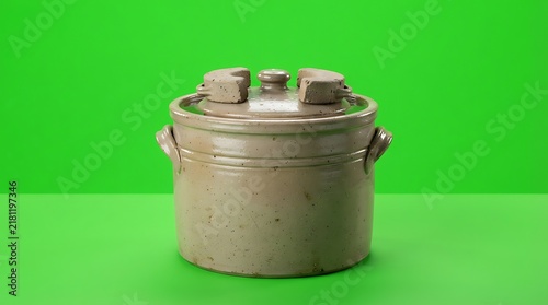 A traditional stoneware fermentation crock isolated on a bright green background