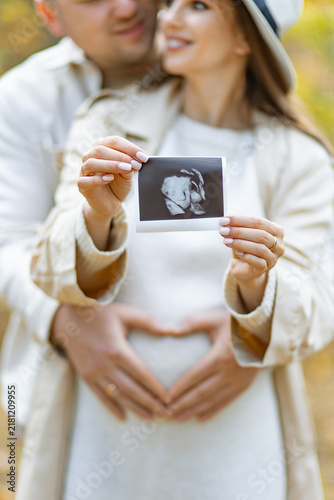 A couple lovingly holds an ultrasound image, celebrating their upcoming parenthood
