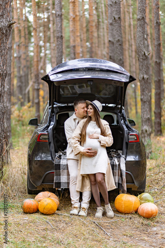 Bild auf Leinwand A loving couple expecting a baby embraces in a beautiful autumn forest, surround