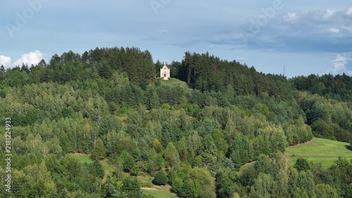 Aerial mountain Chapel St Michael Archangel Blizne. South eastern Poland. Historic mountain valley village with 15th century wooden All Saints Church. Agriculture land, rivers, forest and rural farm.