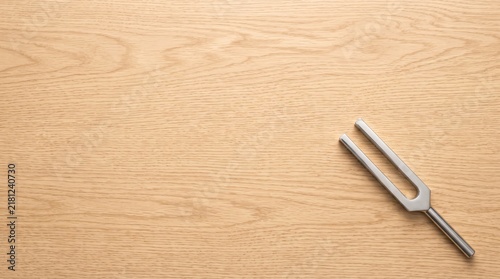 Foto Metal tuning fork placed on a light wooden surface
