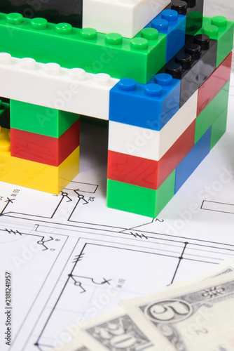 Small house made of toy blocks, housing plan with electric installation and dollar banknotes. Building or renting home