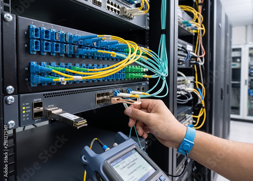 IT Technician Testing Fiber Optic Network Connections in Modern Data Center Server Rack