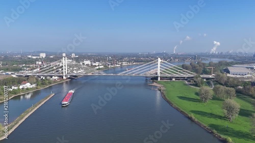 Aerial view of a cargo ship moving on the river under a modern cable stayed bridge during a bright sunny day.