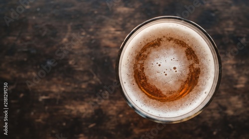 A freshly poured glass of amber beer sits atop a weathered wooden table, sparkling under soft evening light. Bubbles dance on the surface, inviting relaxation and conversation.