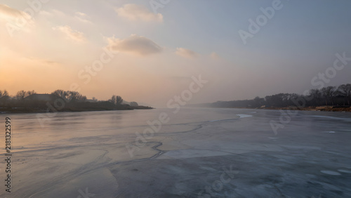 Frozen river landscape under a pale winter sky