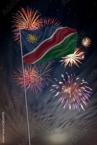 Waving National flag of Namibia and holiday fireworks in night sky