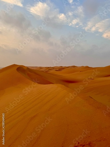 Foto Omani desert, on top of a sand dune, blue sky with a few clouds at sunset hour-