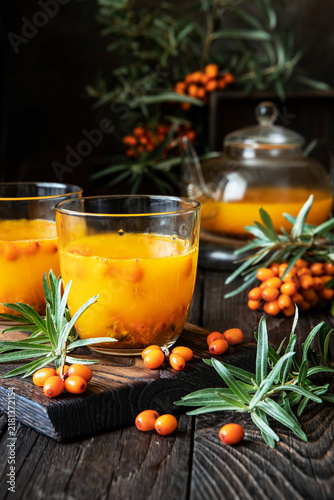Glass cup with healing tea with sea-buckthorn on wooden background