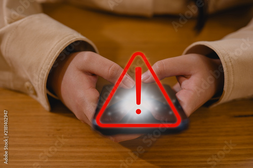 Girl hand or businesswoman using smartphone with red triangle warning sign in concept of risk notification error and maintenance warning and safety privacy data security, risk management