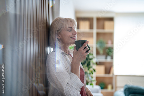 Blonde woman enjoying hot drink, relaxing at home