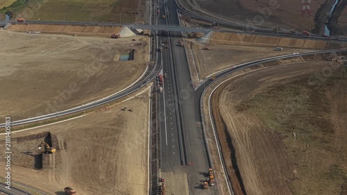 Aerial view of the Autostrada Moldovei A7 junction construction near Bacau, showing highway ramps, overpass, heavy machinery, and earthworks under soft daylight. 4K video.