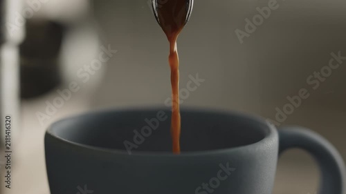 Slow motion closeup shot of espresso poured into blue cup with professional coffee machine