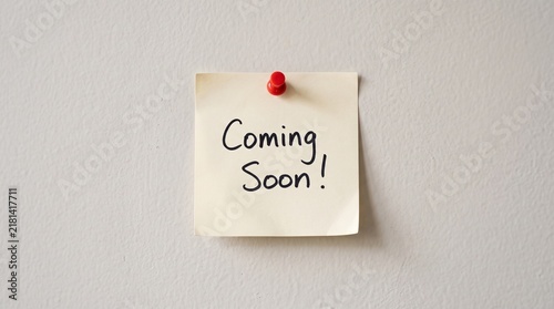 Foto Yellow sticky note with coming soon handwritten message