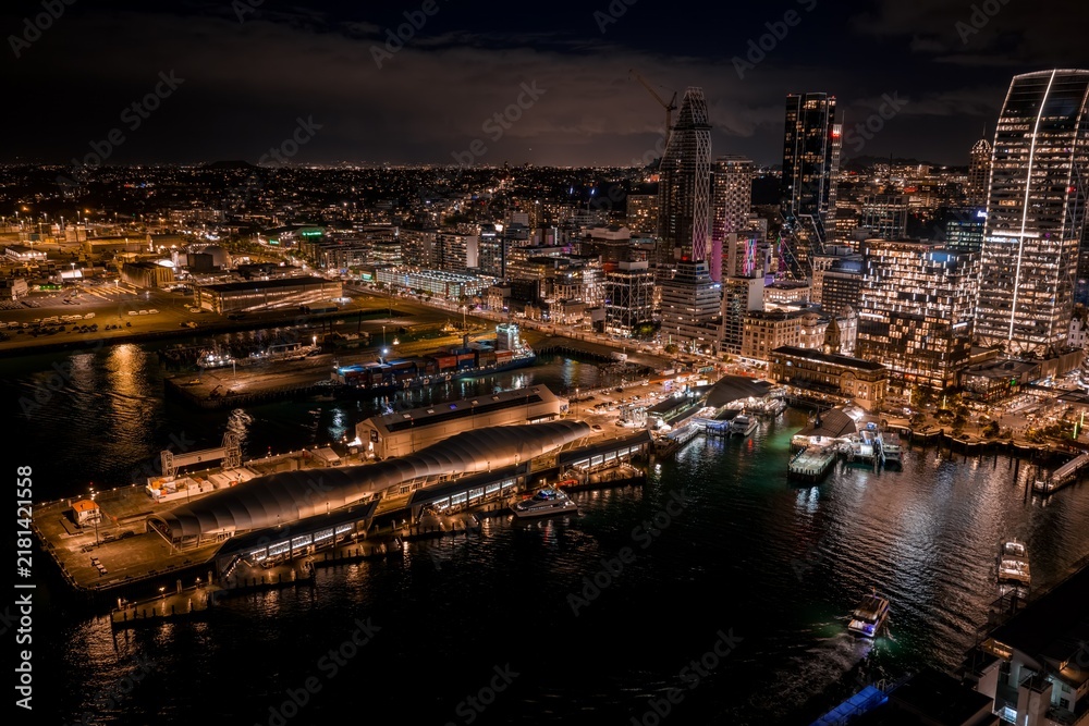Obraz premium Stunning night view of the illuminated Auckland city skyline, harbor, and ferry terminal in Auckland Central, New Zealand.