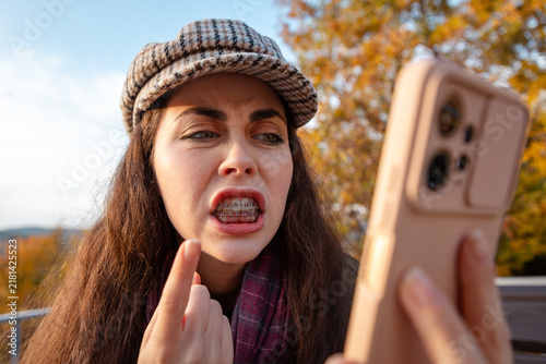 Foto Portrait of young woman expressing anger and disbelief after receiving disturbing information on mobile phone