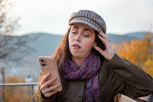 Fotografía Young woman looking puzzled and unimpressed while browsing smartphone content