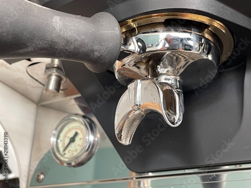 Close-up of a professional espresso machine's portafilter and pressure gauge