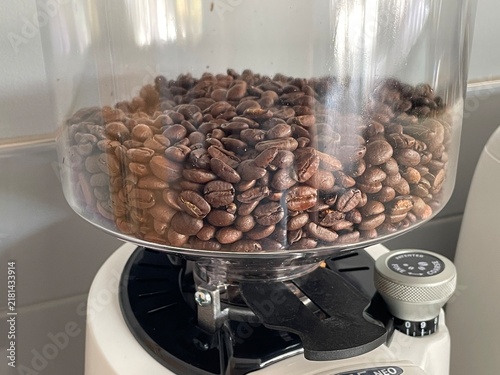 Close-up of roasted coffee beans filling a clear hopper on a grinder