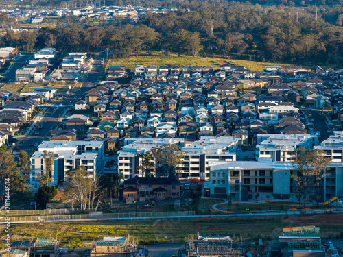 Aerial view of a modern suburban housing estate featuring rows of houses and apartment buildings surrounded by trees and ongoing construction in Tallawong, New South Wales, Australia.