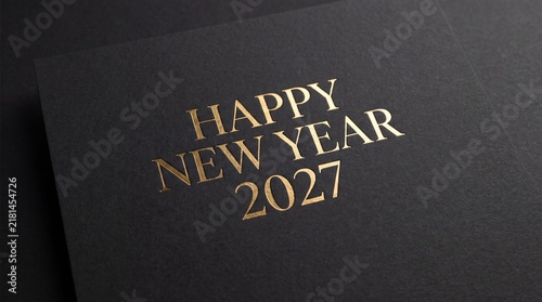 Happy New Year 2027 gold foil letterpress on textured black paper. Elegant holiday greeting card background. High angle close up view
