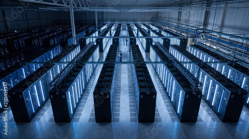 Aerial view of a modern data center floor featuring long rows of glowing server cabinets containing SSD storage. Cool white and blue lighting creates a clean, minimalist industrial tech design.