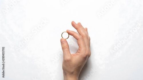 Elegant Gold Wedding Ring Held Delicately Between Fingers On White