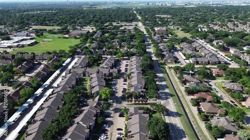 Multifamily apartment blocks flank Parkway Boulevard near Moore Road. Parallel covered vehicle carports, paved driveways, green tree canopies line residential grounds across Coppell, Texas.