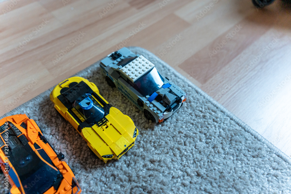 Obraz premium Warsaw, Poland - Sep 4, 2026: Row of LEGO Technic model cars in orange, yellow and blue on a gray rug